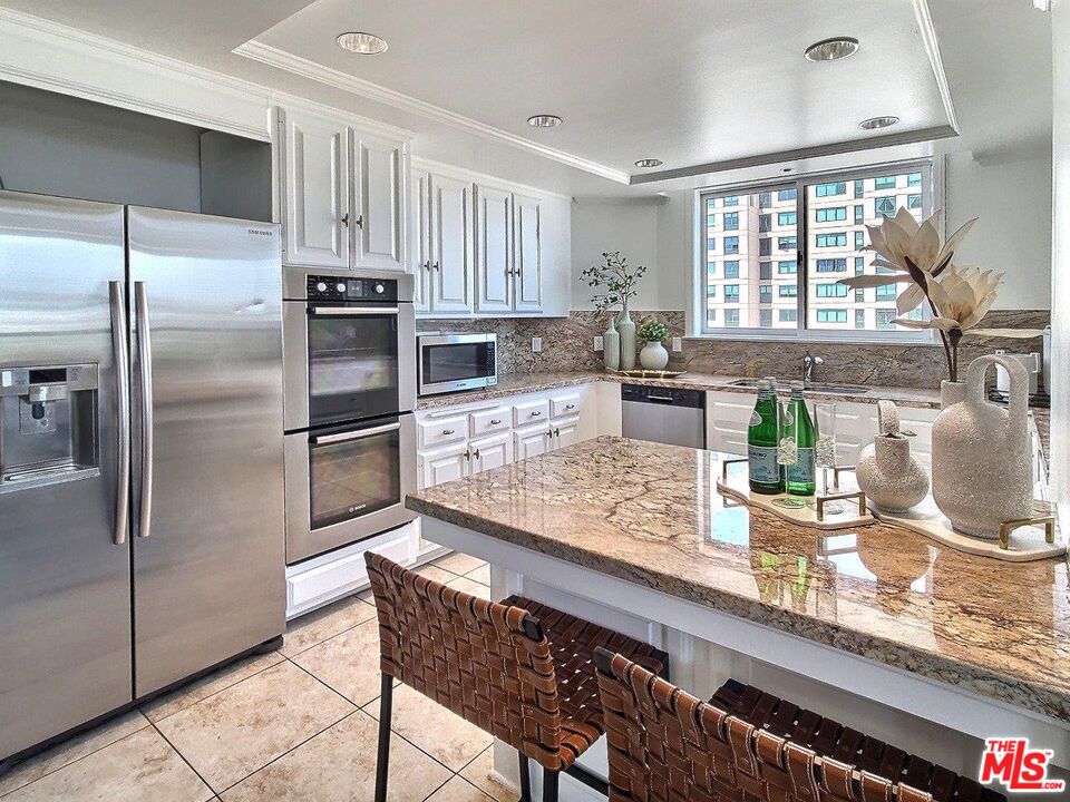 10550 Wilshire Boulevard, Unit 1004 Los Angeles, CA 90024 - Photo 21 of 39 a kitchen with granite countertop a refrigerator and wooden cabinets
