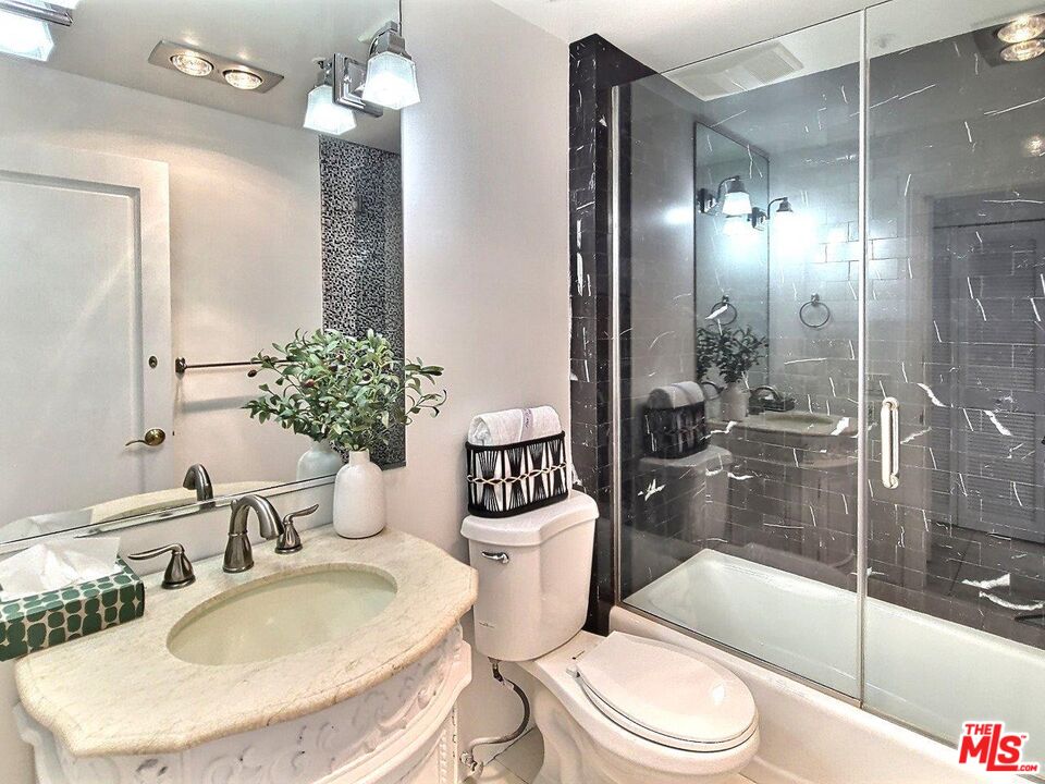 10550 Wilshire Boulevard, Unit 1004 Los Angeles, CA 90024 - Photo 36 of 39 a bathroom with a sink a toilet a glass door shower and a mirror