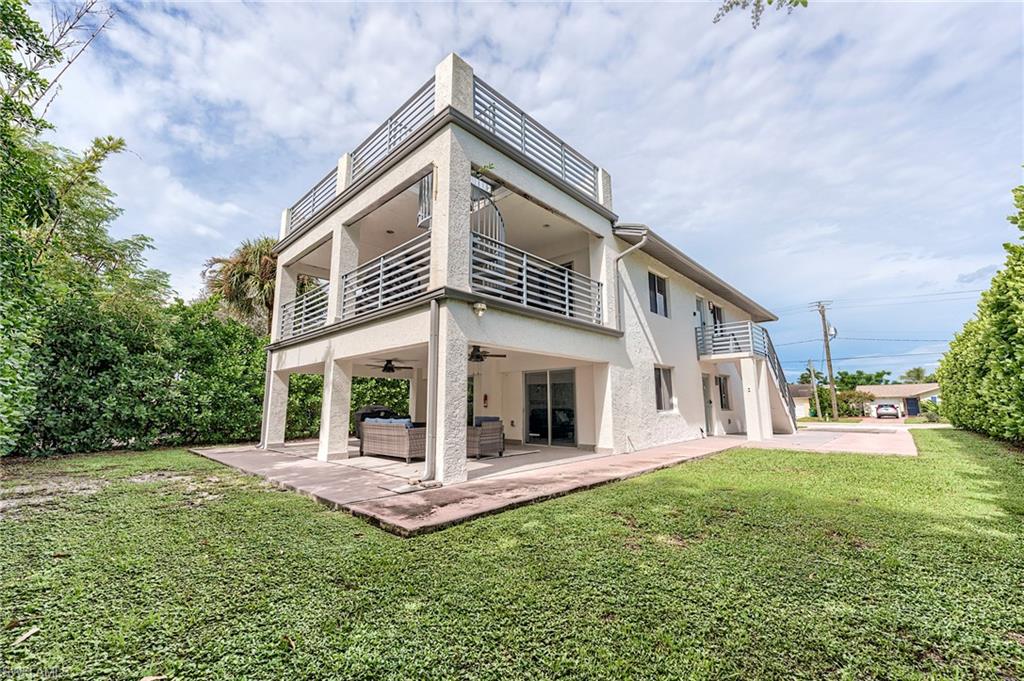 145 Capri Boulevard Naples, FL 34113 - Photo 12 of 33 a view of a white house with a big yard and large trees