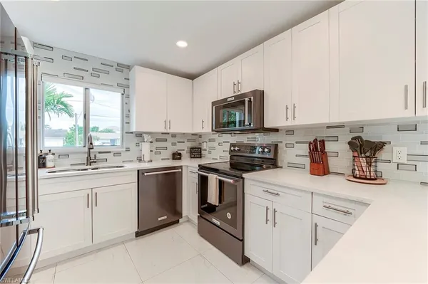 a kitchen with white cabinets sink and appliances