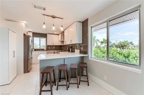 a kitchen with kitchen island a large window appliances and cabinets