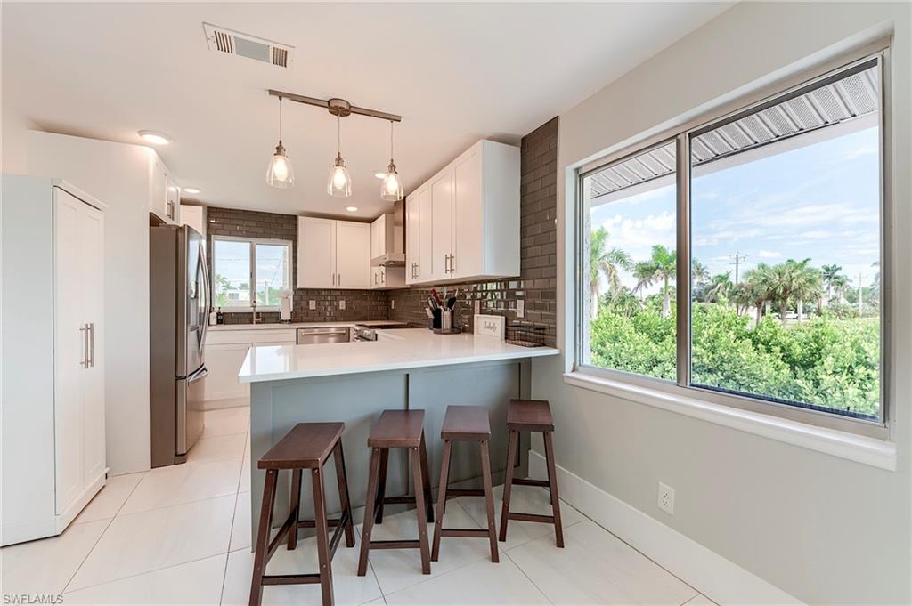 145 Capri Boulevard Naples, FL 34113 - Photo 2 of 33 a kitchen with kitchen island a large window appliances and cabinets