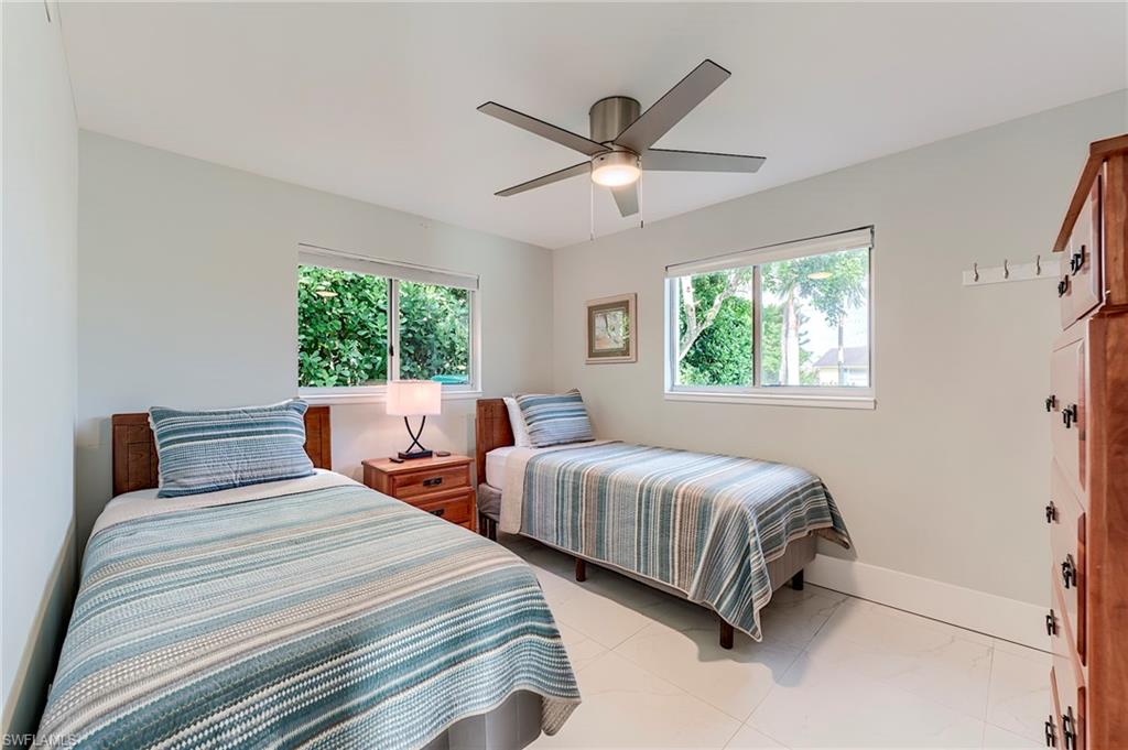 145 Capri Boulevard Naples, FL 34113 - Photo 24 of 33 a bedroom with two beds and a chandelier