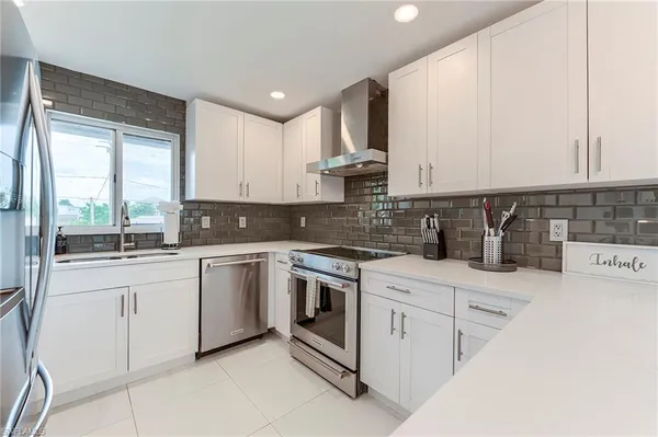 a kitchen with stainless steel appliances granite countertop white cabinets a sink and a stove