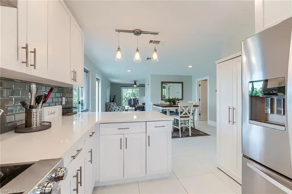 a kitchen with white cabinets and chandelier