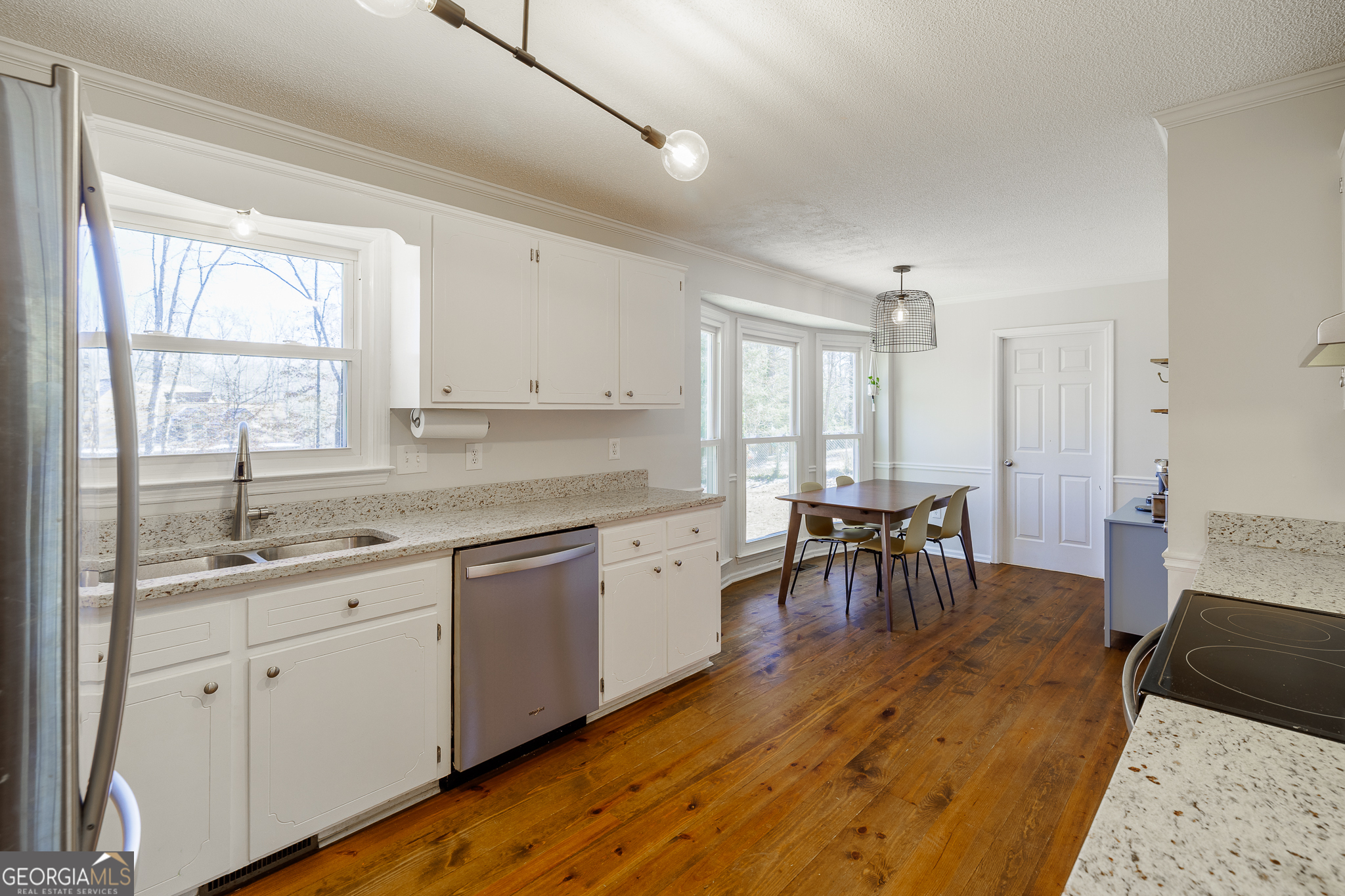 415 Brookstone Drive Athens, GA 30605 - Photo 16 of 55 a large white kitchen with granite countertop a stove a sink a dining table and chairs with wooden floor