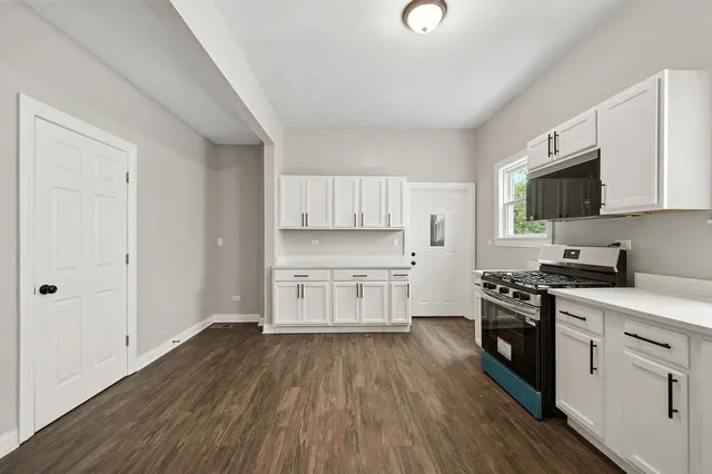 a kitchen with a hard wood floor white cabinets and stainless steel appliances