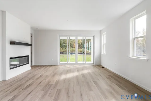 an empty room with wooden floor fireplace and windows