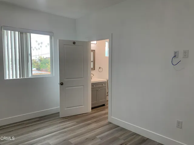 an empty room with wooden floor cabinet and windows