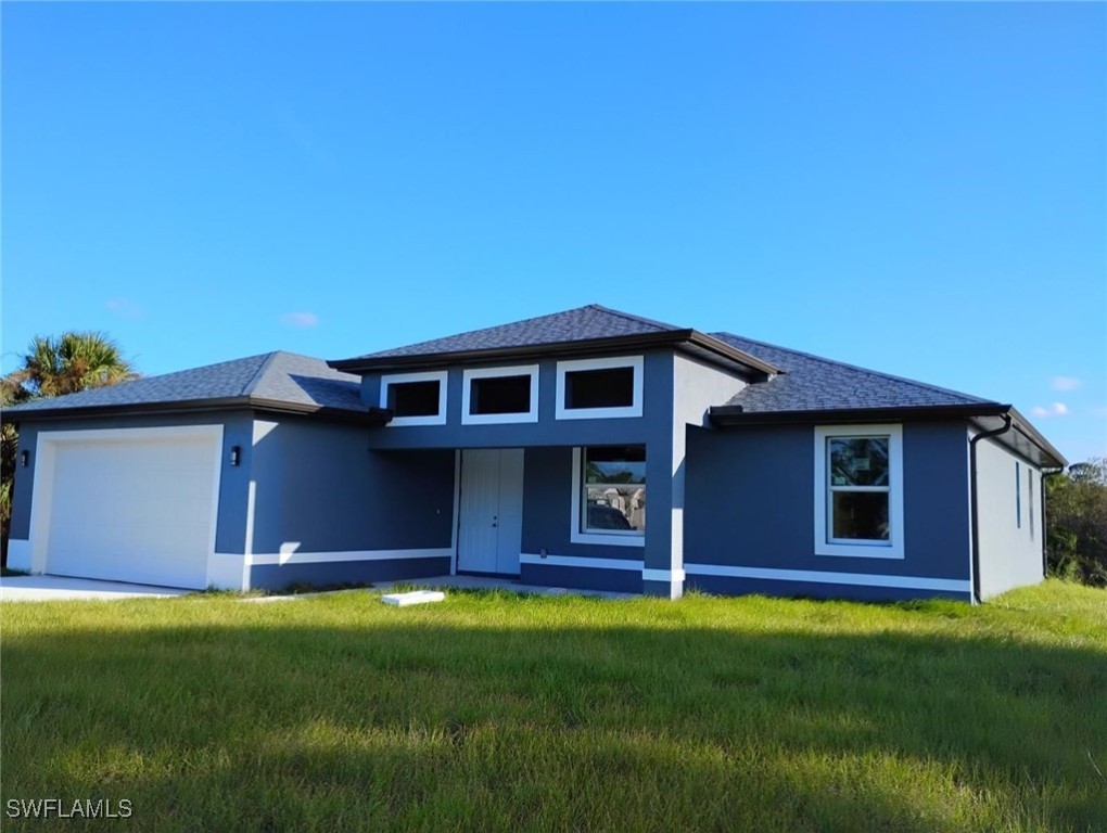 1244 Jaguar Boulevard Lehigh Acres, FL 33974 - Photo 1 of 1 a front view of a house with a garden