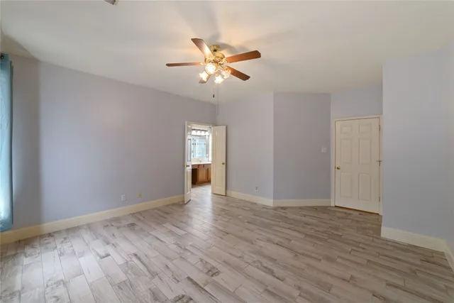 a view of an empty room with window and wooden floor