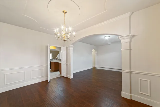 an empty room with wooden floor chandelier and entryway