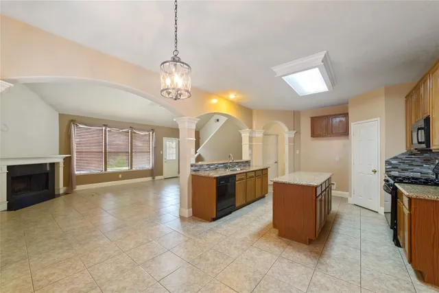 a large kitchen with granite countertop a stove a sink dishwasher and a refrigerator with wooden floor