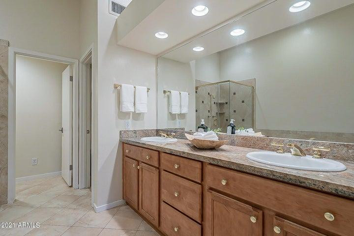 7700 East Gainey Ranch Road, Unit 153 Scottsdale, AZ 85258 - Photo 18 of 24 a bathroom with a granite countertop double vanity sink and mirror