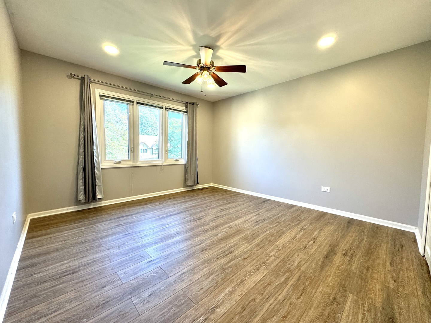 1398 East Gartner Road Naperville, IL 60540 - Photo 17 of 31 an empty room with wooden floor chandelier fan and windows