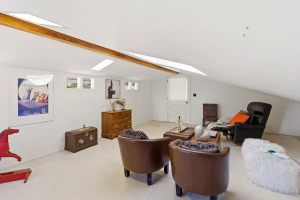 a living room with couches a computer on a desk and next to a window