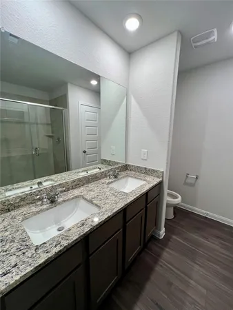 a bathroom with a granite countertop sink a toilet and a shower
