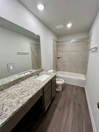 a bathroom with a granite countertop sink a toilet and shower