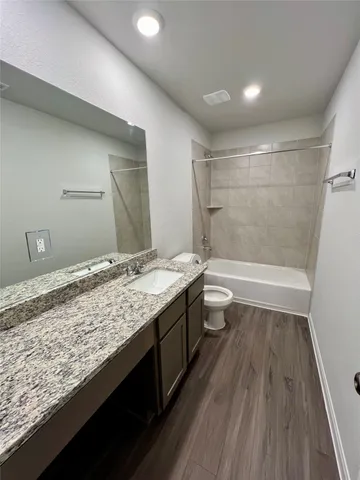 a bathroom with a granite countertop sink a toilet and shower