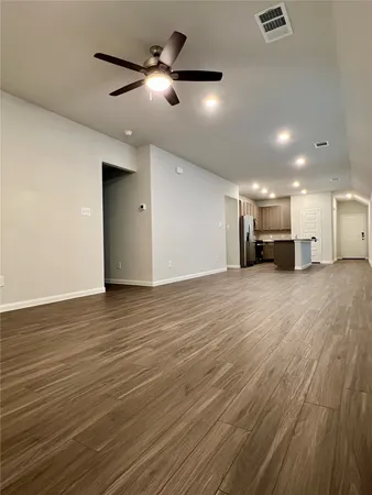 an empty room with wooden floor a ceiling fan and windows