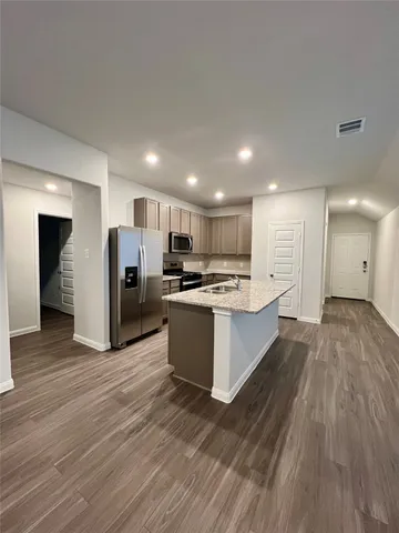 a large kitchen with a center island wooden floor stainless steel appliances and cabinets