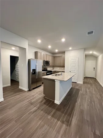 a large kitchen with a center island wooden floor stainless steel appliances and cabinets
