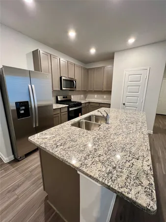 a kitchen with stainless steel appliances granite countertop a sink refrigerator and microwave