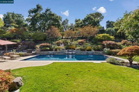 a view of swimming pool with lawn chairs and plants