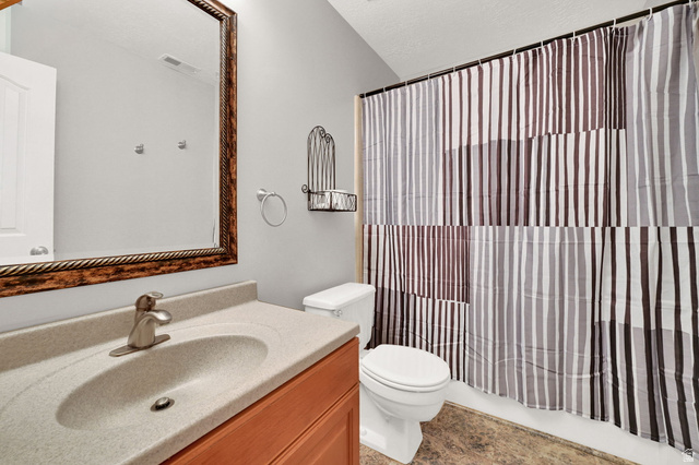 4792 Glasmann Way South Ogden, UT 84403 - Photo 51 of 70 Full bathroom featuring a vanity with an integrated sink, wood-finish cabinetry, a framed wall mirror, and a toilet