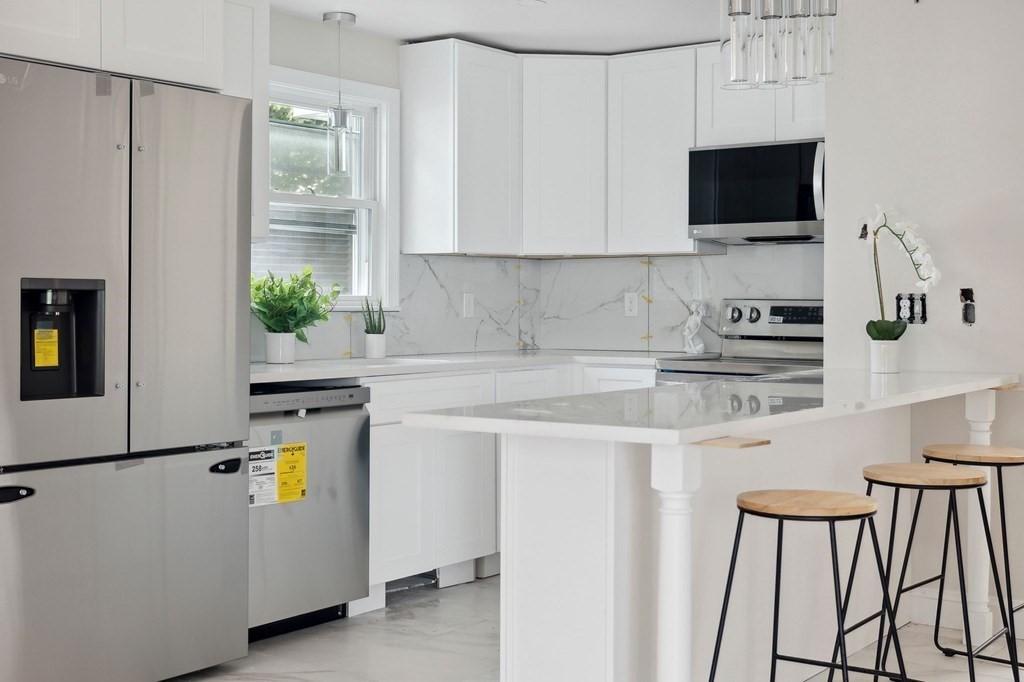 9-13 Sutherland Road, Unit 2 Arlington, MA 02476 - Photo 2 of 15 a kitchen with stainless steel appliances a stove a refrigerator a sink a stove and white cabinets with wooden floor