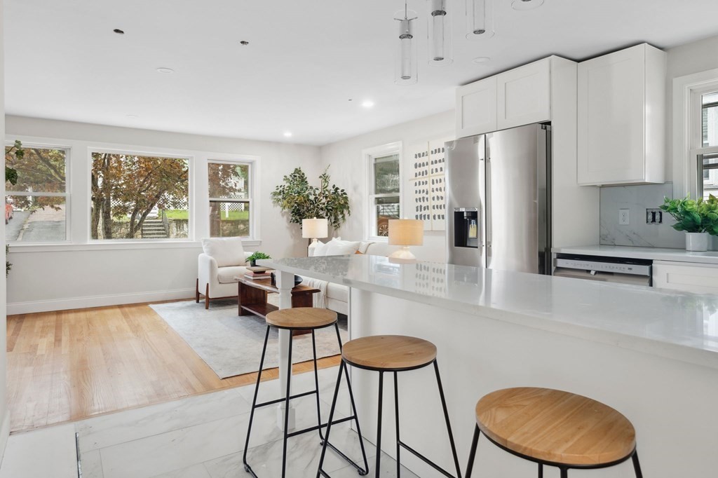 9-13 Sutherland Road, Unit 2 Arlington, MA 02476 - Photo 3 of 15 a kitchen with stainless steel appliances granite countertop a refrigerator a stove a sink dishwasher and white cabinets with wooden floor