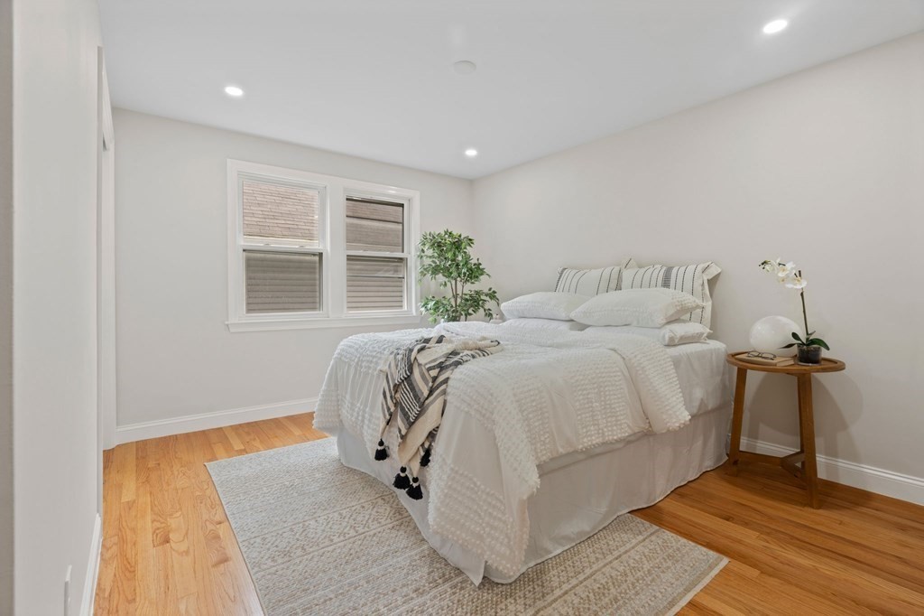 9-13 Sutherland Road, Unit 2 Arlington, MA 02476 - Photo 7 of 15 a bed sitting in a spacious bedroom next to a window and a chandelier