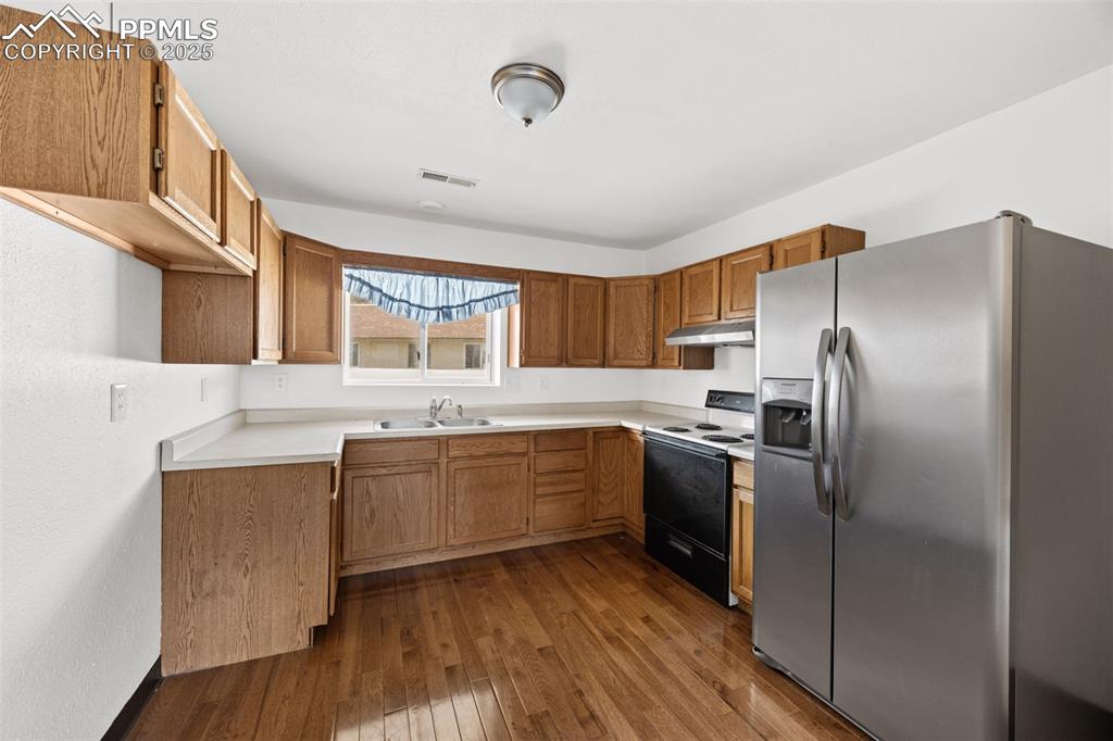2131 Preuss Road, Unit A Colorado Springs, CO 80910 - Photo 7 of 17 a kitchen with stainless steel appliances granite countertop a refrigerator a sink dishwasher a stove with wooden cabinets and floor
