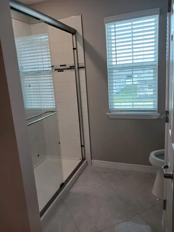 a view of an empty room with wooden floor and a ceiling fan