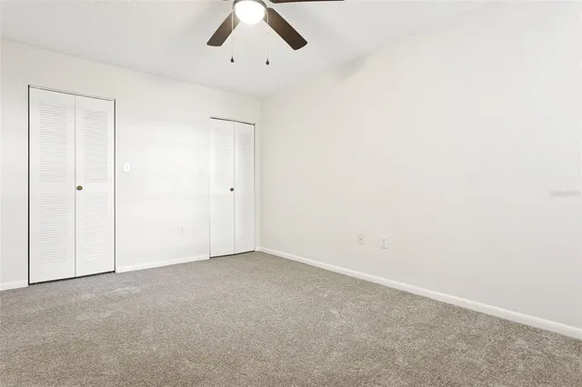 an empty room with a window and a fan