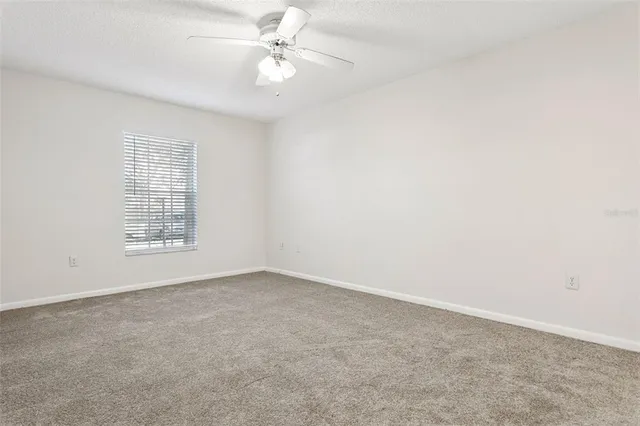an empty room with a chandelier fan and closet area
