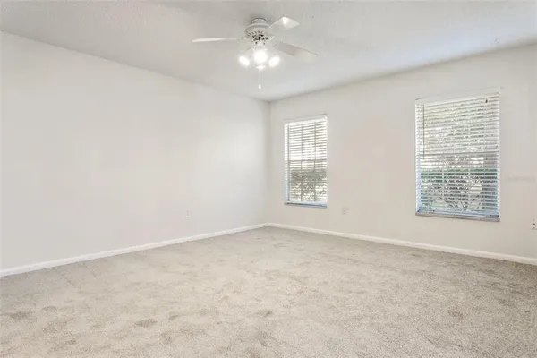 an empty room with windows and chandelier fan
