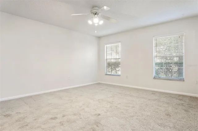 an empty room with windows and chandelier fan