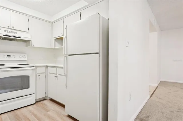 a white refrigerator freezer and a stove sitting inside of a kitchen