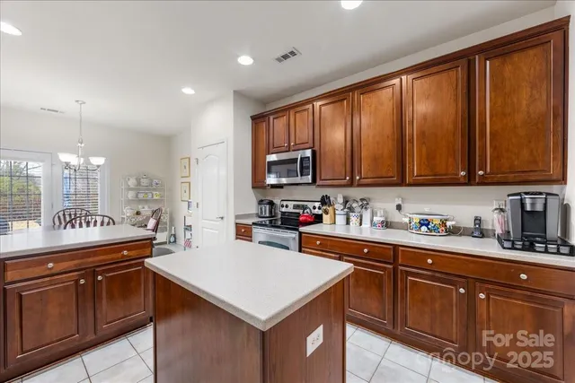 a kitchen with stainless steel appliances a sink a stove a refrigerator cabinets and a window