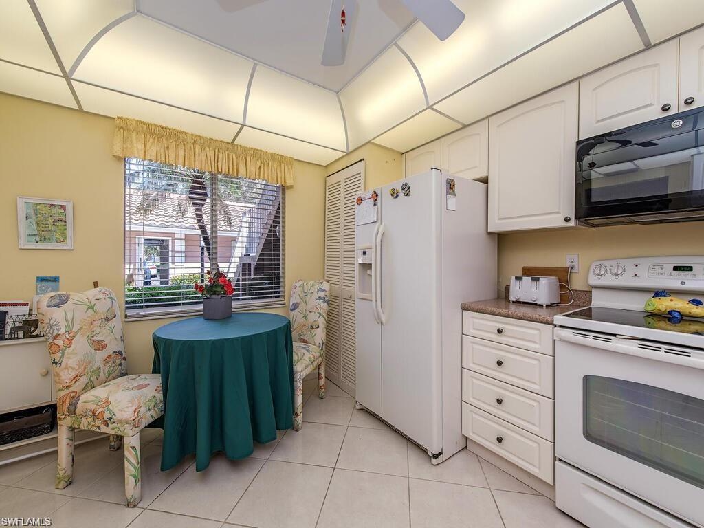 5932 Cranbrook Way, Unit C106 Naples, FL 34112 - Photo 7 of 13 Kitchen featuring white appliances, white cabinetry, light tile patterned flooring, and a ceiling fan