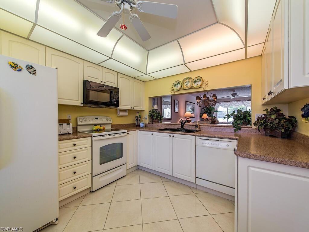 5932 Cranbrook Way, Unit C106 Naples, FL 34112 - Photo 8 of 13 Kitchen with white appliances, dark countertops, a sink, a ceiling fan, and light tile patterned floors