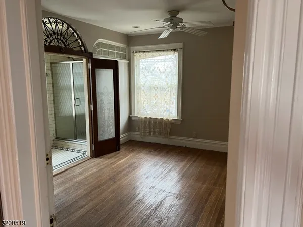 a view of an empty room with wooden floor and a window