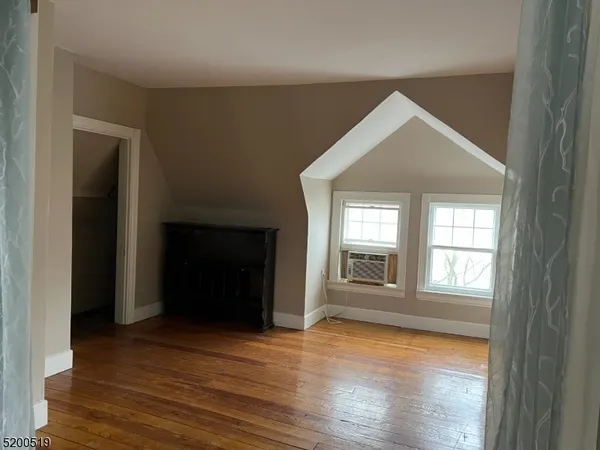 an empty room with wooden floor cabinet and windows