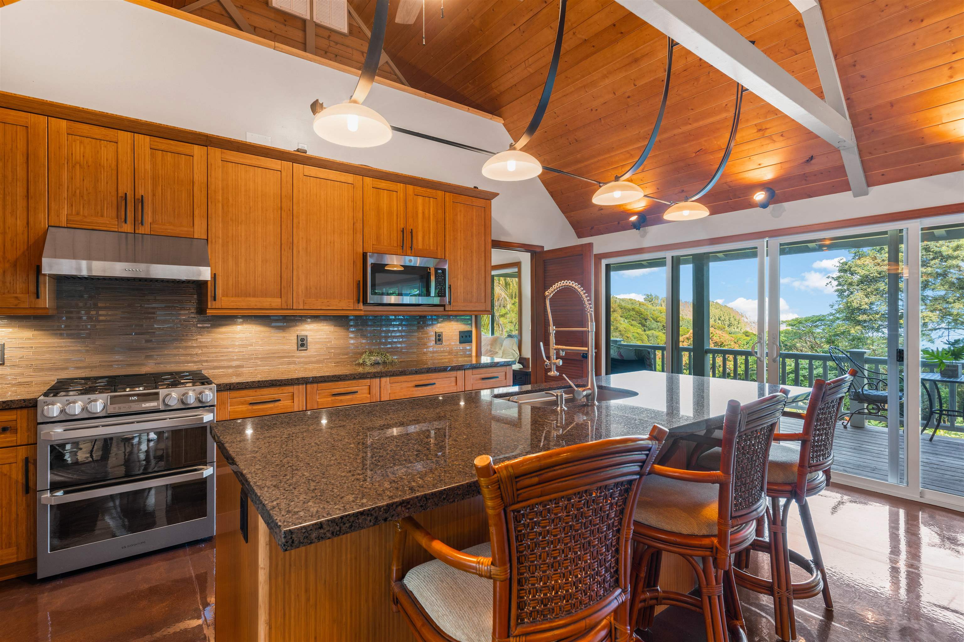 655 Kulike Road, Unit B Haiku, HI 96708 - Photo 12 of 38 a kitchen with stainless steel appliances granite countertop a stove a refrigerator a microwave oven with a dining table and chairs