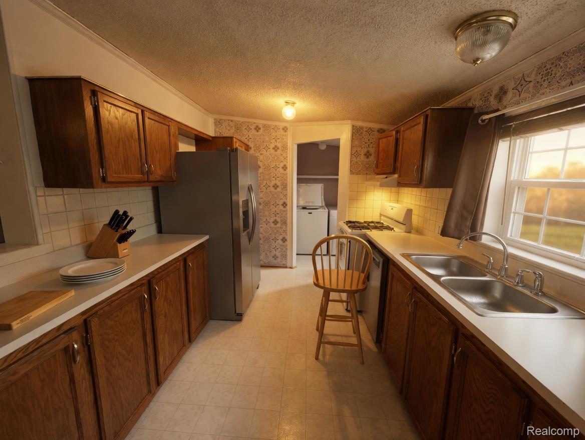 6988 McKean Road Ypsilanti, MI 48197 - Photo 4 of 21 Kitchen featuring wallpapered walls, a textured ceiling, light floors, light countertops, and stainless steel appliances