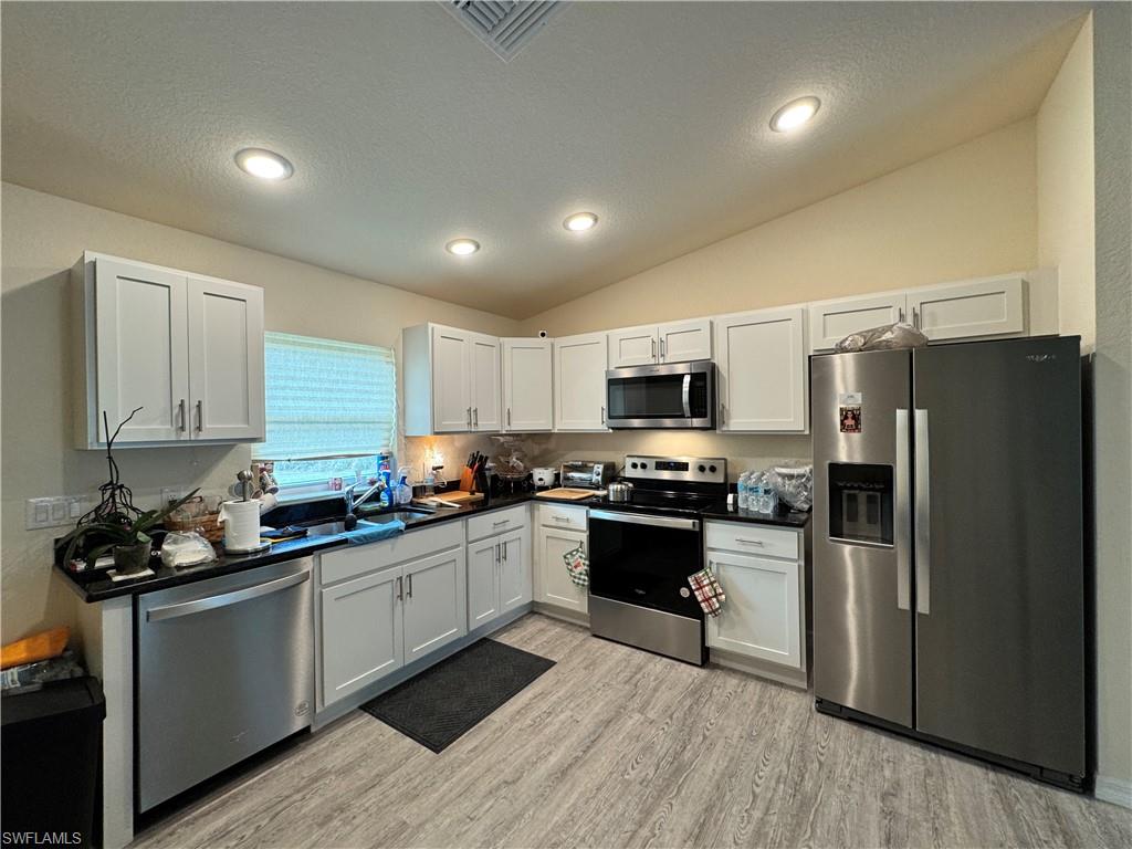 108 Dublin Circle LaBelle, FL 33935 - Photo 7 of 12 a kitchen with stainless steel appliances granite countertop a refrigerator a sink dishwasher a stove top oven a refrigerator and white cabinets with wooden floor