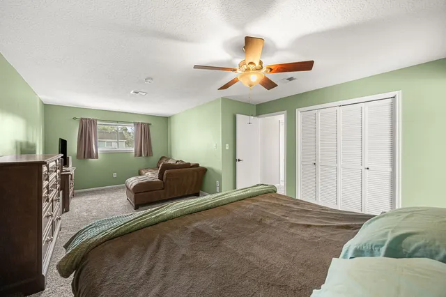a bedroom with a large bed and ceiling fan