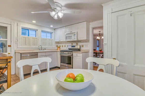 a kitchen with stainless steel appliances a white table and chairs in it