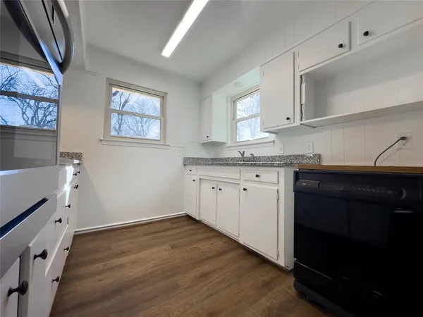 a kitchen with granite countertop a sink cabinets and wooden floor